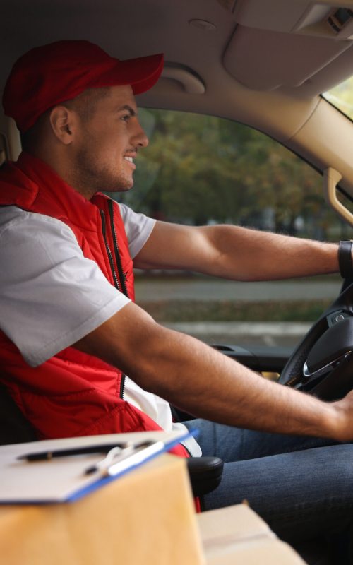 Courier in uniform on driver's seat of car